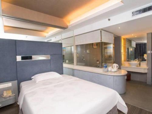 a bedroom with a large white bed and a bathroom at Friendship Hotel in Shenzhen