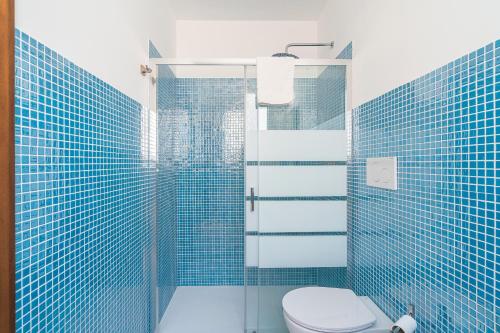 a blue tiled bathroom with a toilet and a shower at Ognissanti Holiday House in Ragusa