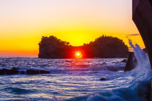 a sunset over the ocean with a rock formation at TAOYA Shirahama Senjyo in Shirahama