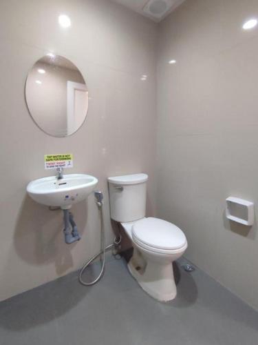 a bathroom with a toilet and a sink and a mirror at One Serenata Hotel General Trias in Silang