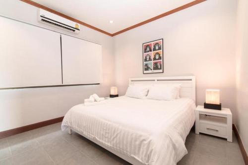 ein weißes Schlafzimmer mit einem weißen Bett und einem Fenster in der Unterkunft Thailand Resort Hotel in Hua Hin