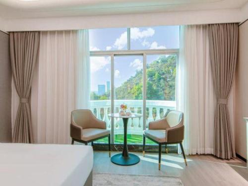 a bedroom with a table and chairs and a large window at Zhuhai Dehan Hotel in Zhuhai