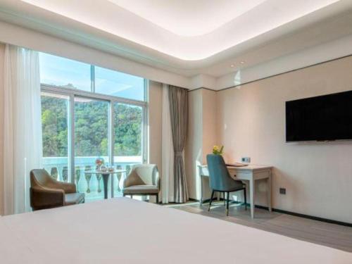 a hotel room with a bed and a desk and a television at Zhuhai Dehan Hotel in Zhuhai