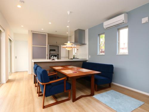 a kitchen and dining room with a wooden table and blue chairs at Dog Resort D&K-ドッグリゾートD&K- in Futtsu