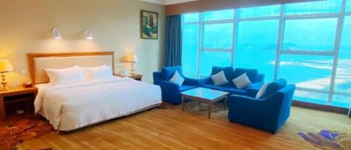 a bedroom with a bed and two blue chairs at Zhuhai Dehan Hotel in Zhuhai