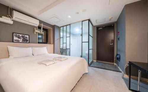 um quarto com uma grande cama branca e uma porta de vidro em Hotel TreeShade Dongdaemun em Seul