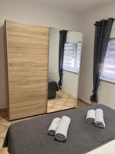 a mirror in a bedroom with two towels on a bed at Apartmani Ivanic in Vir