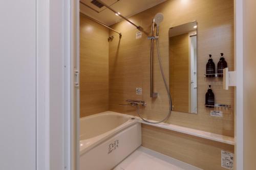 東京にあるThe Apartment Hotel 恵比寿1のバスタブとシャワー付きのバスルーム