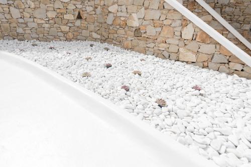 a pile of white rocks next to a stone wall at Cova Mykonos Suites in Elia Beach