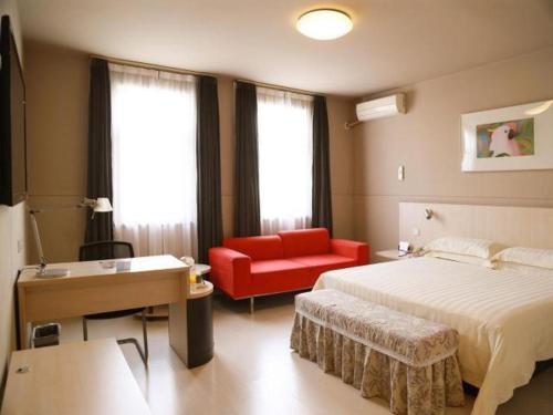 a hotel room with a bed and a red chair at Jinjiang Inn Yueyang Railway Station in Yueyang