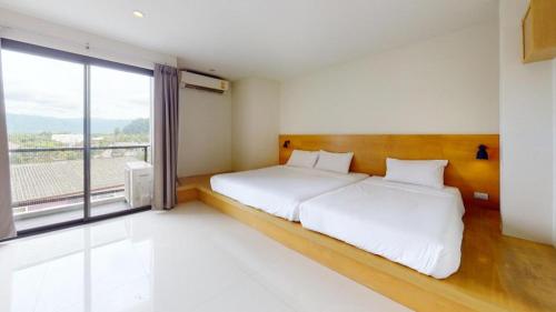 a bedroom with a bed and a large window at Le Park Hotel in Nakhon Si Thammarat