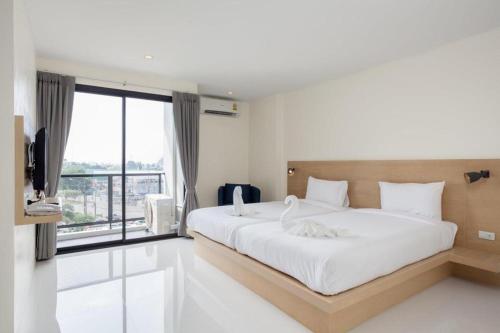 a bedroom with a large bed and a large window at Le Park Hotel in Nakhon Si Thammarat
