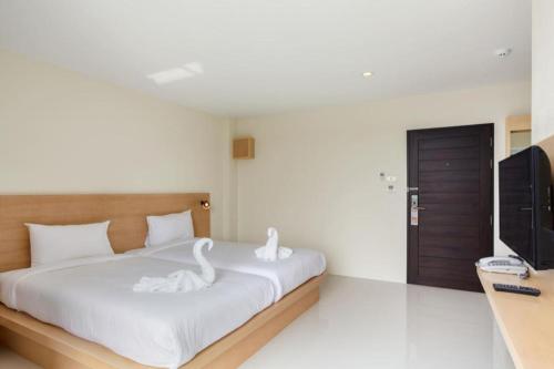 two white swans sitting on a bed in a bedroom at Le Park Hotel in Nakhon Si Thammarat
