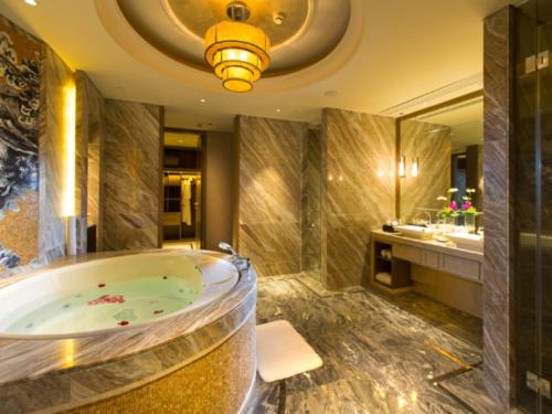 a bathroom with a tub and a large mirror at New Century Grand Hotel Hangzhou Zheshang in Yuhang