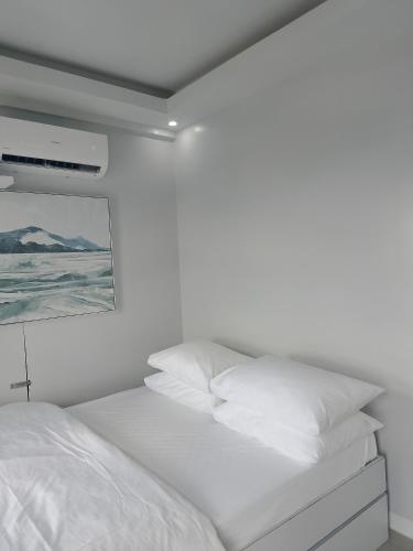 a white bedroom with a bed with white pillows at Urban Oasis with Skyline View in Manila