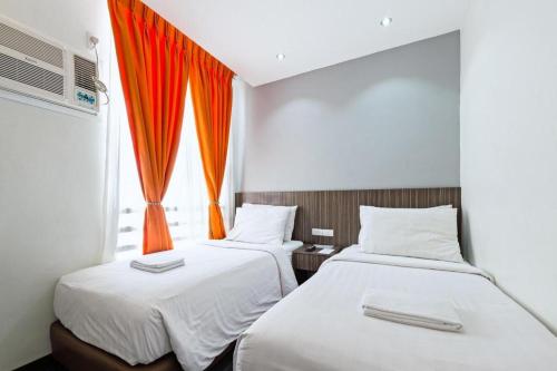 two beds in a room with an orange curtain at Eighty Eight Hotel in Koronadal