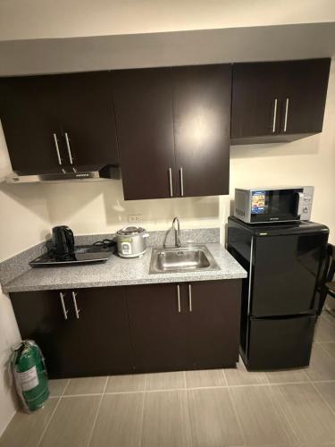 une petite cuisine avec un évier et un micro-ondes dans l'établissement NFr, à Manille