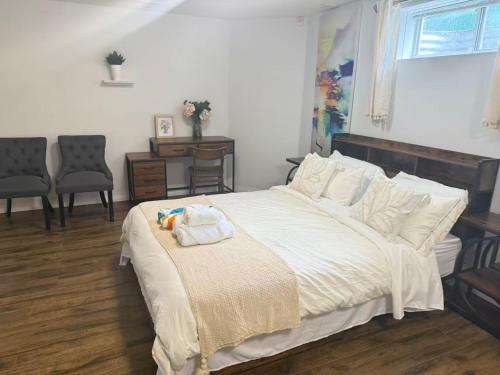 a bedroom with a large bed with white sheets and chairs at Park side Basement 2 bedroom suite in Kelowna