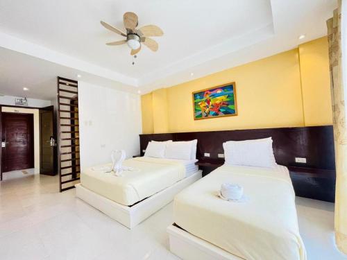 um quarto com duas camas e um ventilador de teto em Alice in Wonderland Beach Hotel em Boracay