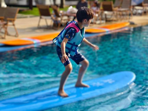 a young boy on a surfboard in the water at The Mangrovetree Sanya Resort in Sanya