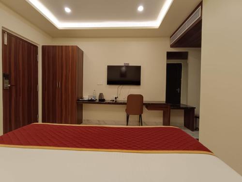 a bedroom with a bed and a desk and a television at Hotel Royal Inn in Tiruvannāmalai