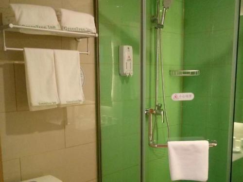 a green bathroom with a shower with a glass door at GreenTree Inn Qingdao Jiaozhou Jiaoping Road Express Hotel in Qingdao