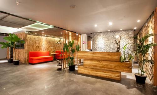 a lobby with a red couch and plants in it at Hotel Daun Bali Seminyak in Seminyak