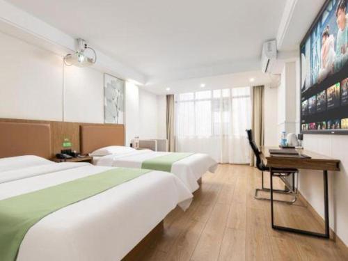 a hotel room with two beds and a desk at GreenTree Inn Haikou City Wuzhishan Road in Haikou