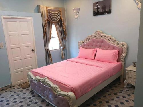 a bedroom with a bed with pink sheets and a window at Chateau de Sangkhlaburi in Sangkhla Buri
