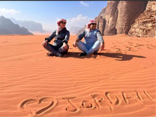 two women kneeling in the desert with the word vacation written in the sand at Star Wars luxury camp in Wadi Rum
