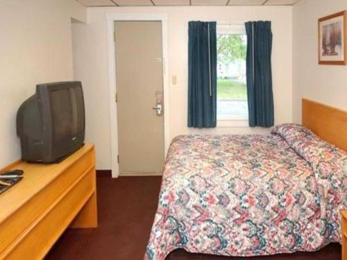 a hotel room with a bed and a tv at Rodeway Inn in Rutland