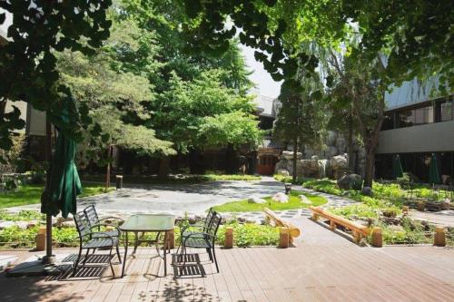 a patio with a table and chairs in a garden at Capital Hotel in Beijing