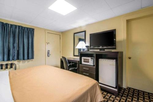 a hotel room with a bed and a flat screen tv at Rodeway Inn in Rutland