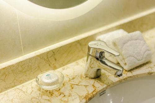 a bathroom sink with a faucet on a counter at Huachen Kenzo Hotel Hangzhou in Hangzhou