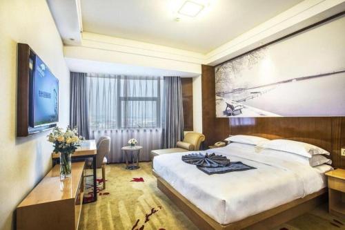 a hotel room with a large bed and a desk at Huachen Kenzo Hotel Hangzhou in Hangzhou