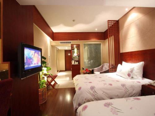 a hotel room with two beds and a flat screen tv at Huachen Kenzo Hotel Hangzhou in Hangzhou