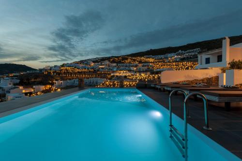 a pool with a view of a city at night at Cova Mykonos Suites in Elia Beach