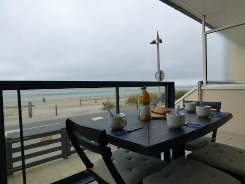 - une table avec des chaises et une vue sur la plage dans l'établissement Les Pieds dans l'Eau, studio terrasse face mer, à Fort-Mahon-Plage