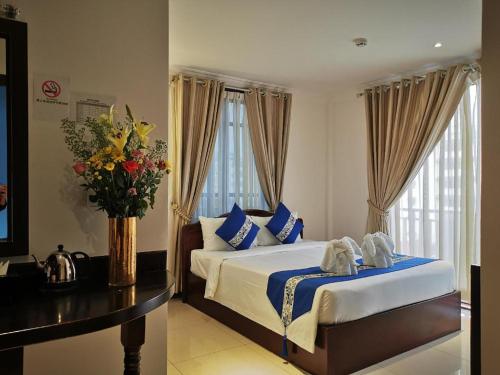 a bedroom with a bed and a vase of flowers at Jun Yue Hotel in Phnom Penh