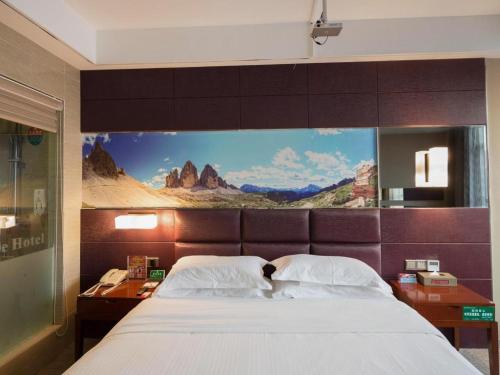 a bedroom with a large bed with a painting on the wall at GreenTree Alliance Shenzhen Shekou Sea World Hotel in Shenzhen