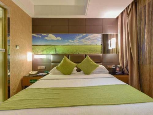 a bedroom with a large bed with a painting on the wall at GreenTree Alliance Shenzhen Shekou Sea World Hotel in Shenzhen