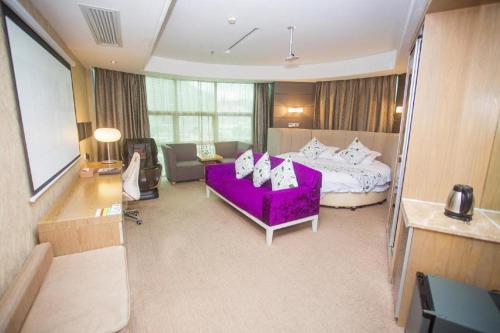 a large room with a purple bed and a couch at GreenTree Alliance Shenzhen Shekou Sea World Hotel in Shenzhen