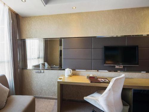 a room with a desk with a tv on the wall at GreenTree Alliance Shenzhen Shekou Sea World Hotel in Shenzhen