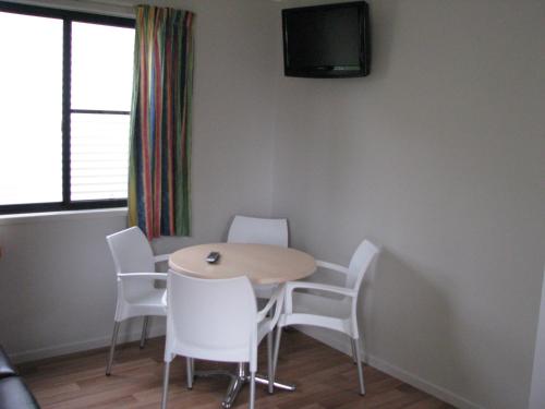 a dining room with a table and white chairs at Cardwell Beachcomber Motel & Tourist Park in Cardwell