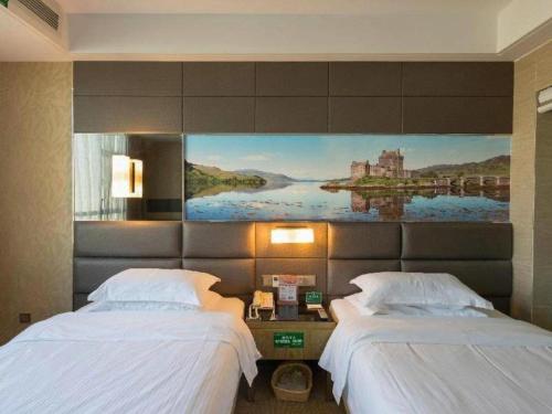 two beds in a hotel room with a painting on the wall at GreenTree Alliance Shenzhen Shekou Sea World Hotel in Shenzhen