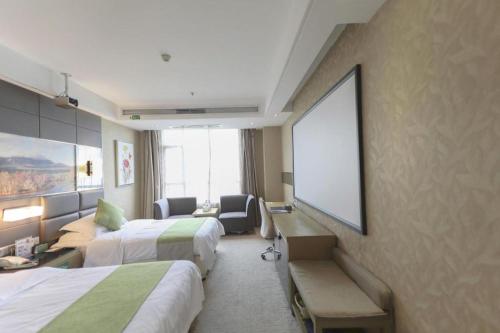 a hotel room with two beds and a projection screen at GreenTree Alliance Shenzhen Shekou Sea World Hotel in Shenzhen