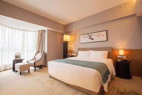 a hotel room with a large bed and a chair at Chambery Hotel in Zhuhai