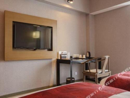 a hotel room with a desk and a television on the wall at Chambery Hotel in Zhuhai