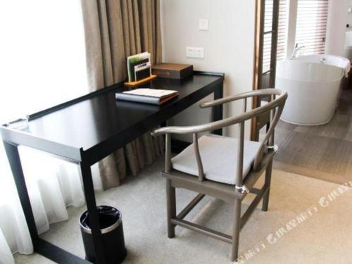 a desk with a chair next to a bath tub at Chambery Hotel in Zhuhai