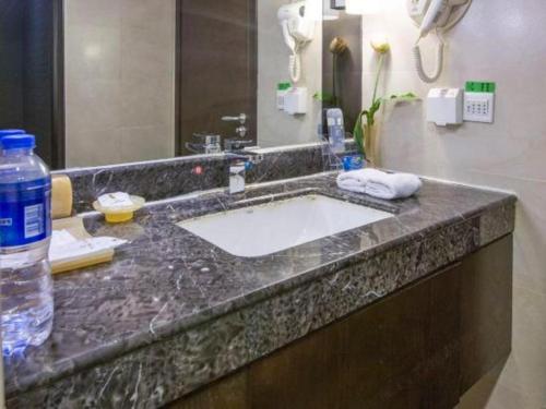 a bathroom counter with a sink with a bottle of water at Tianjin Juchuan Lily Hotel in Binhai